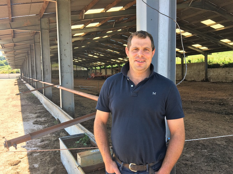 Dairy farmer standing in front of a shed for housing cows